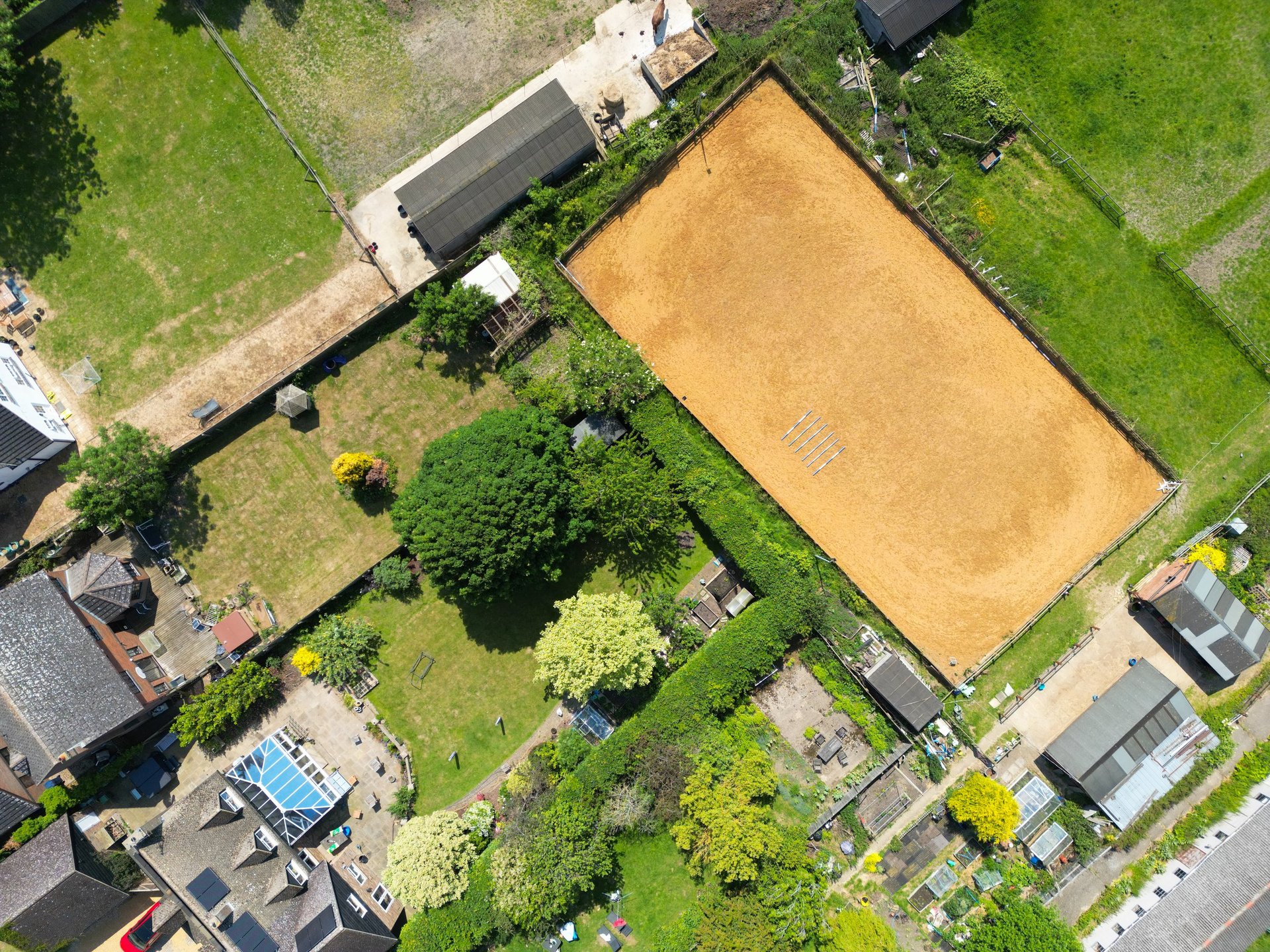 Top down view of equestrian riding arena with sand footing and white railings